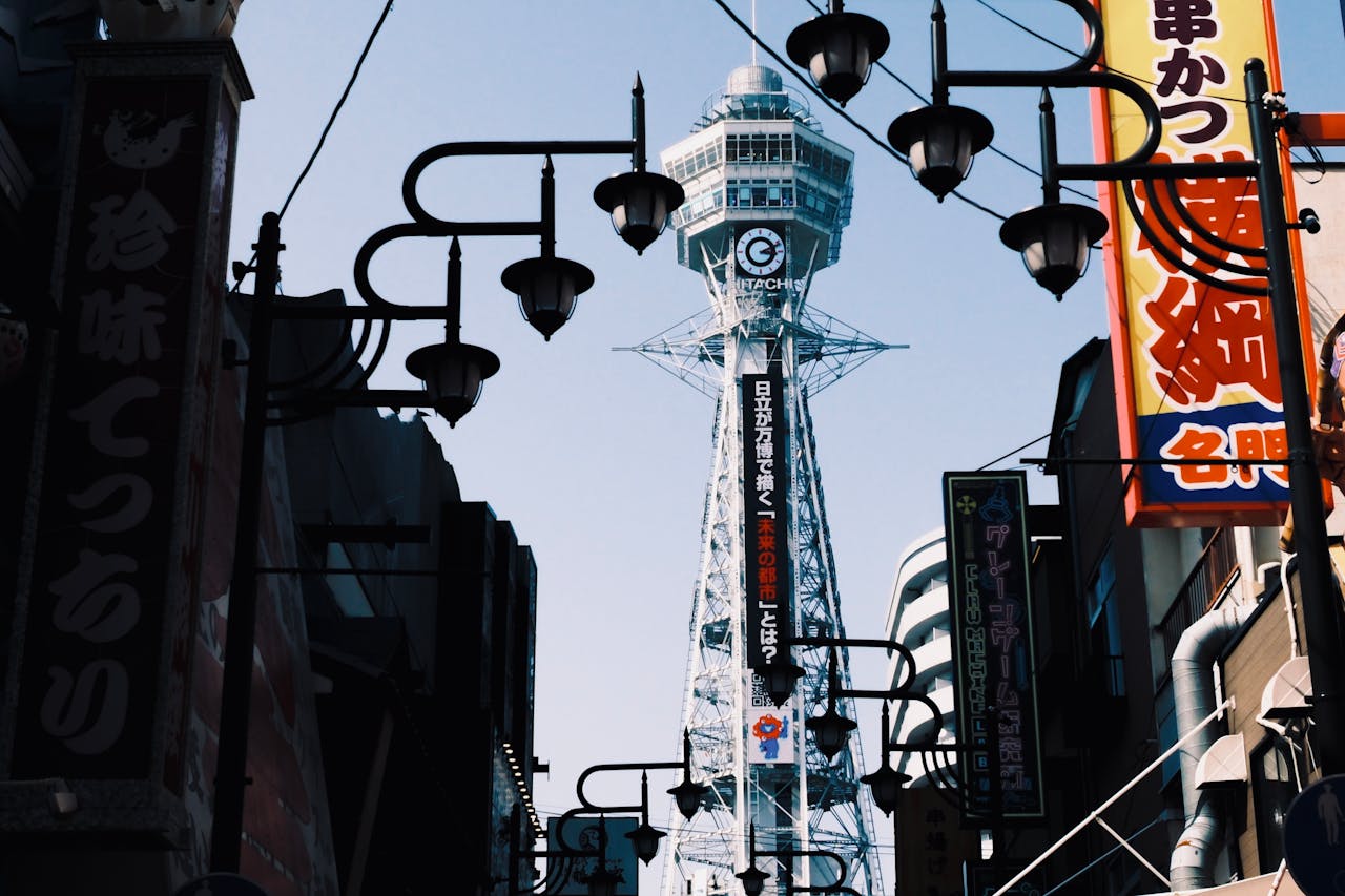 Tsutenkaku Tower in Osakas vibrant Shinsekai district framed by traditional street lamps.