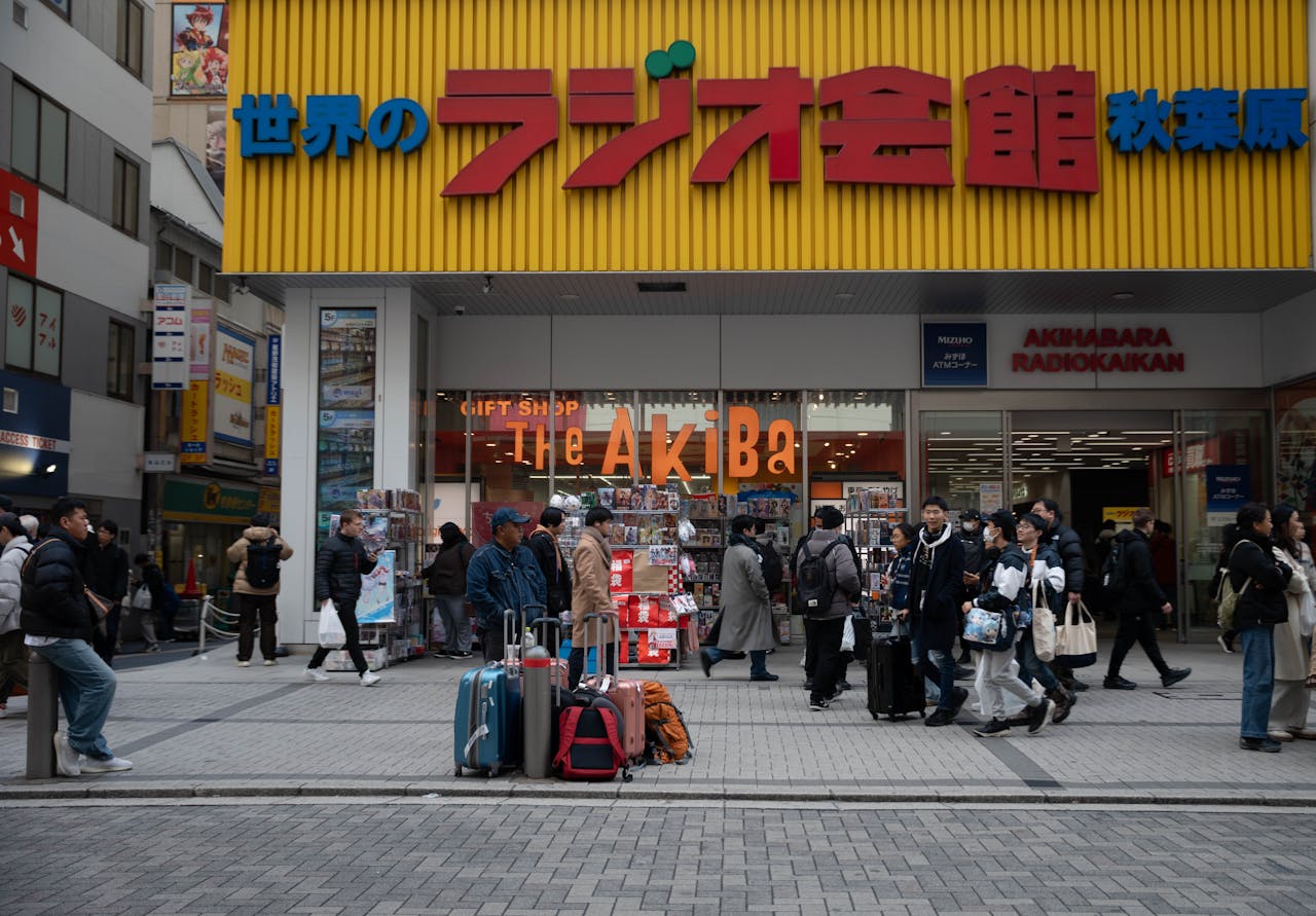 Crowds with luggage at Akihabara Radiokaikan, Tokyo, a hub for electronics and pop culture.